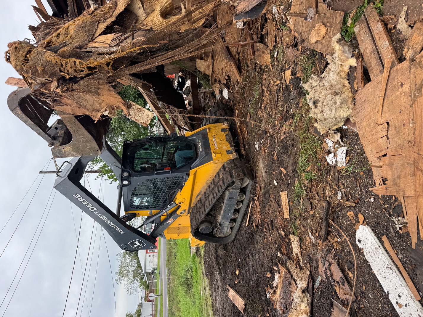 Active house demolition with debris pile and 28 Blue Construction equipment on site