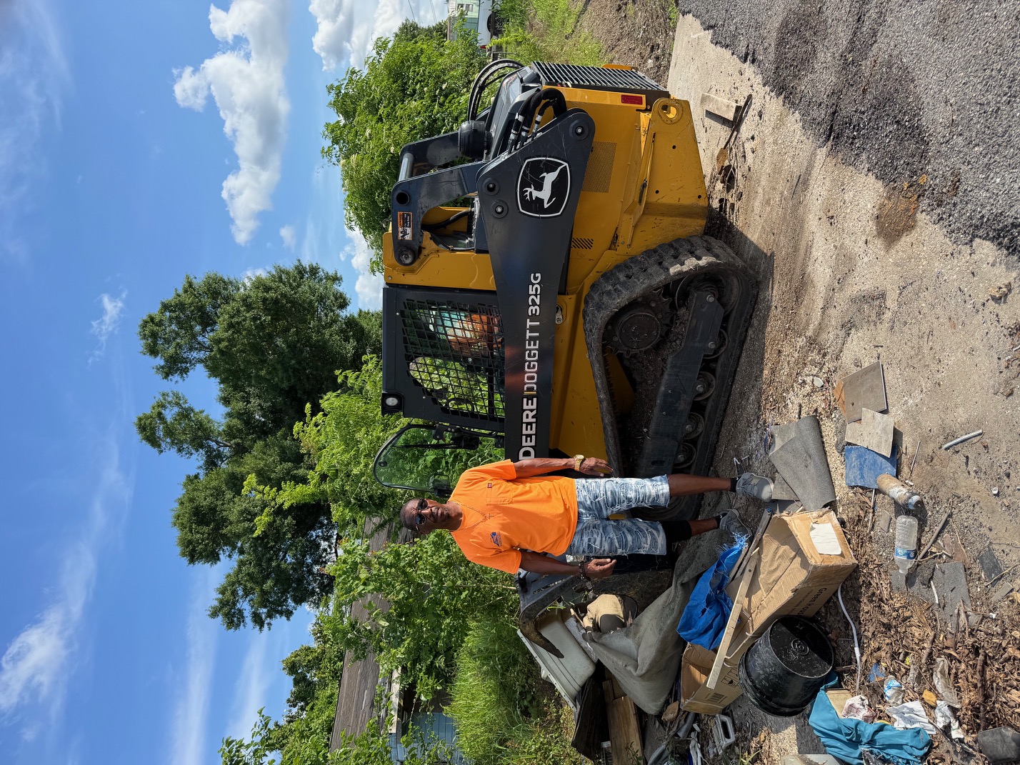 Clarence Clement standing proud with John Deere 325G skid steer loader