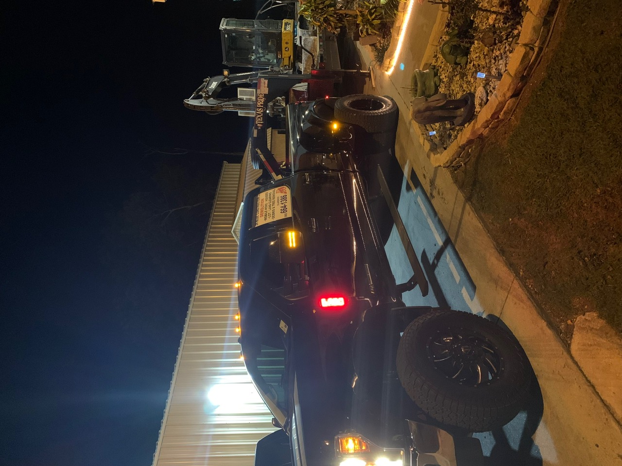 28 Blue Construction branded pickup truck and equipment trailer parked at night