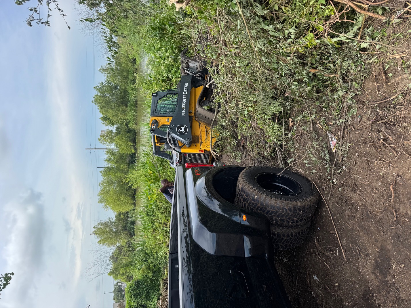 John Deere 326G skid steer loader on trailer ready for site work near bayou