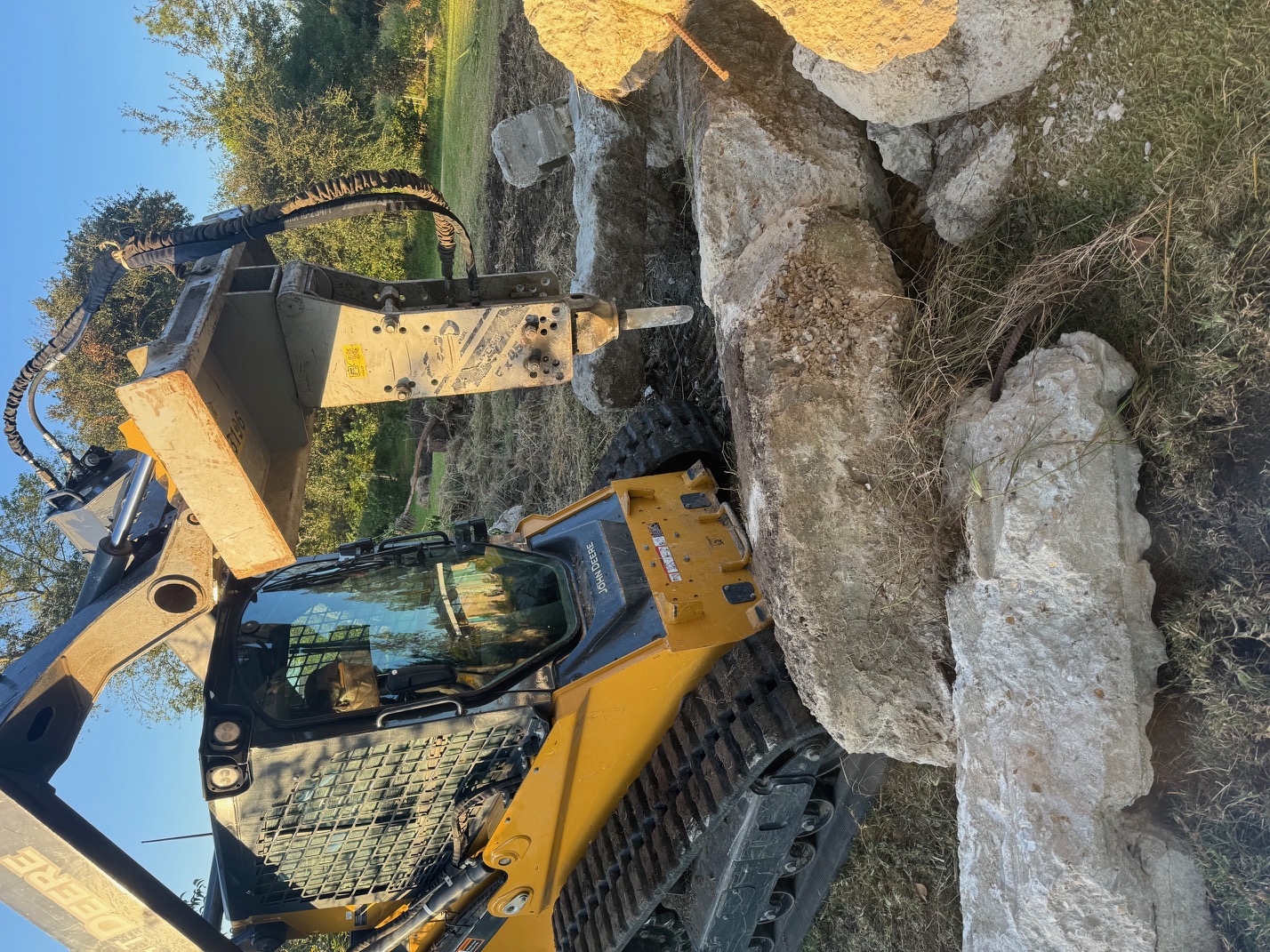 John Deere skid steer with hydraulic breaker demolishing concrete in South Louisiana
