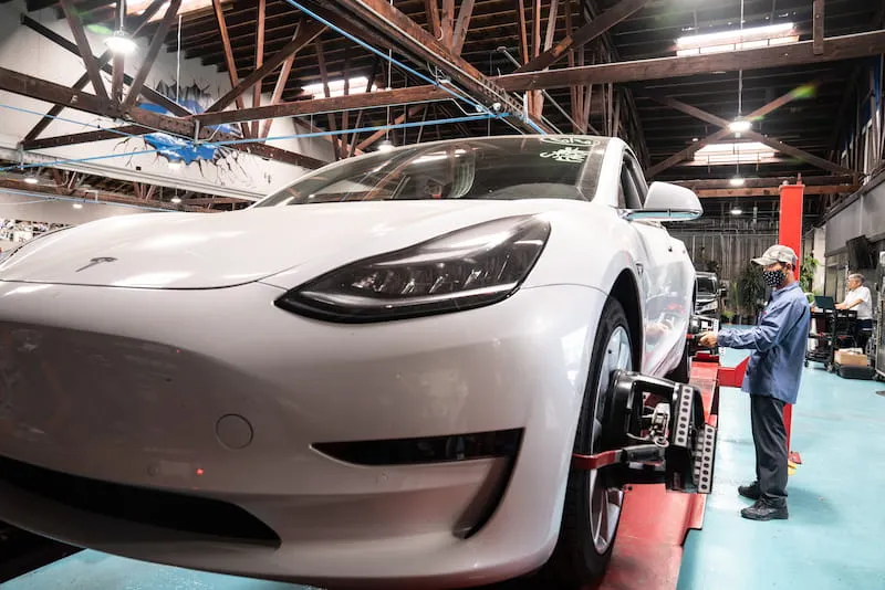 Century Collision Center technician performing expert Tesla collision repair on a white Tesla