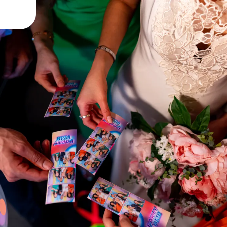 Bride holding photo booth strips at wedding