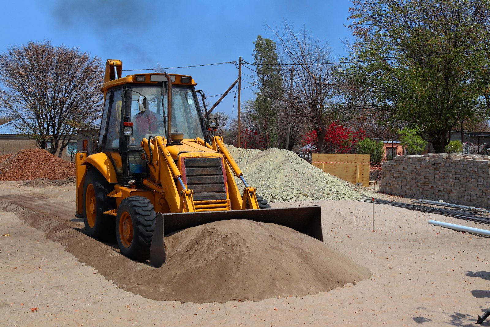 Yellow backhoe loader moving material on a job site — wheel loader and backhoe financing