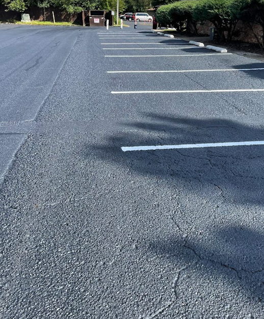 Cracked and faded parking lot before commercial sealcoating service in Fishers