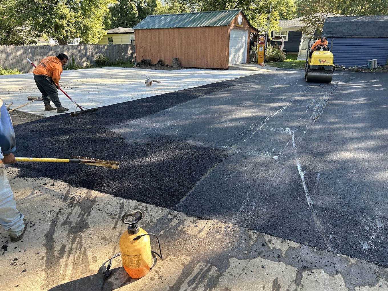 Crew paving new driveway with roller and fresh asphalt in Indianapolis