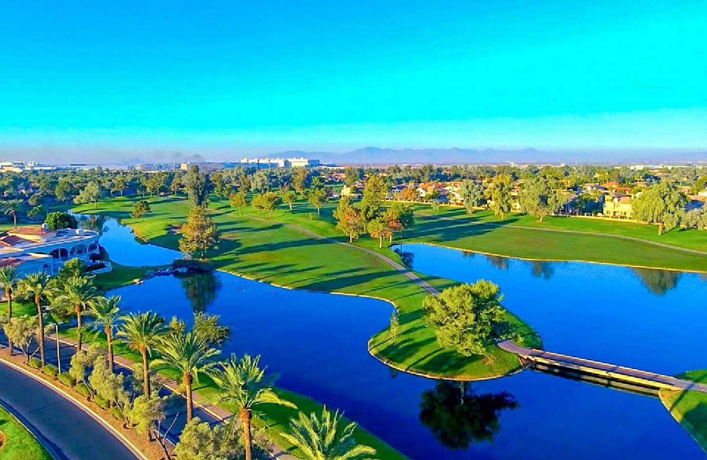 Aerial view of Chandler Arizona showing lush green landscape, lakes, and desert palm trees under bright blue sky
