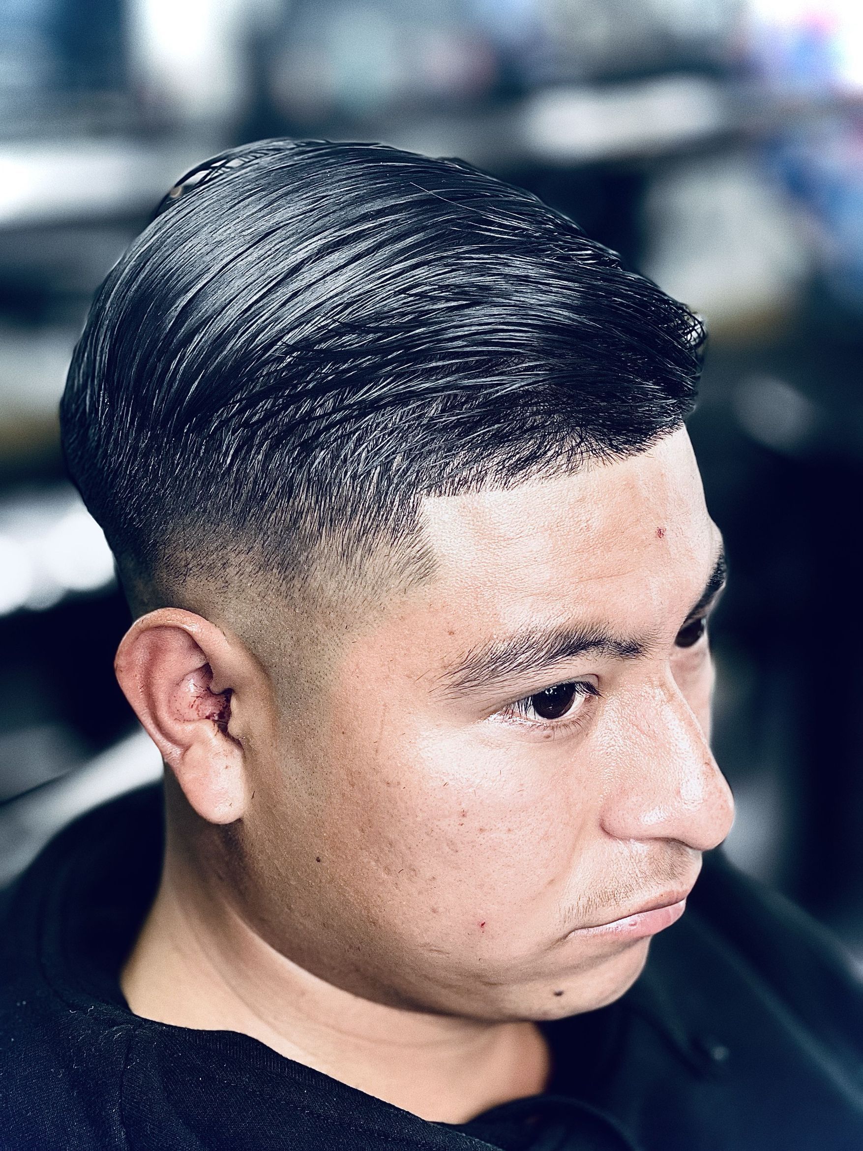 Side profile showing slicked-back styled hair with a smooth fade along the temples and sideburn area