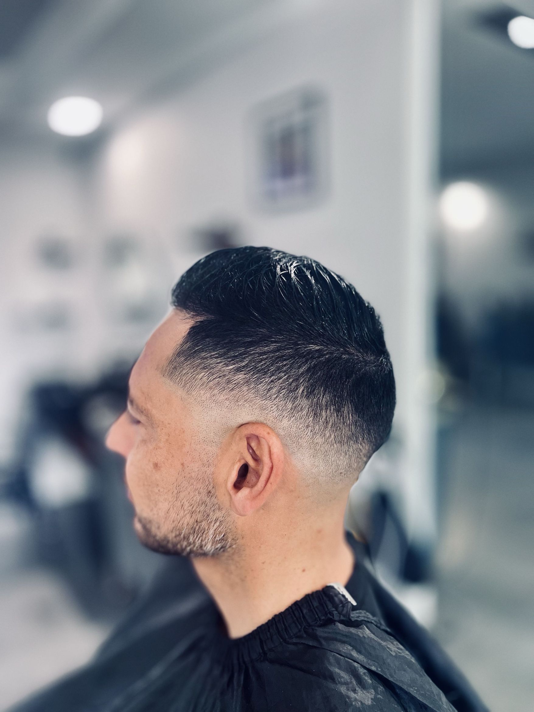 Close-up of a mid fade with neatly combed hair on top, showing clean fade transition around the ear