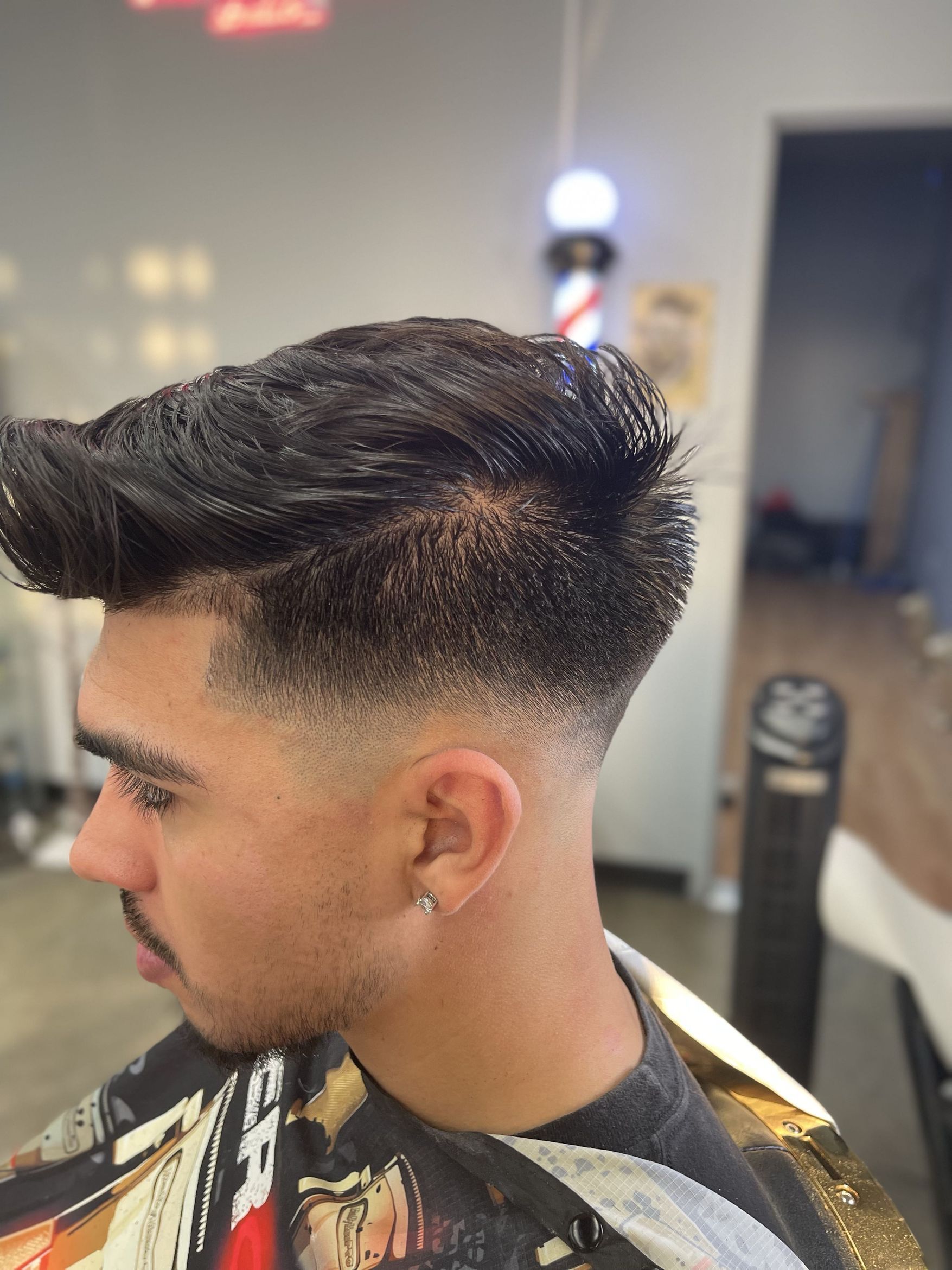 Profile view of a voluminous styled quiff with a tight taper fade on the sides and back