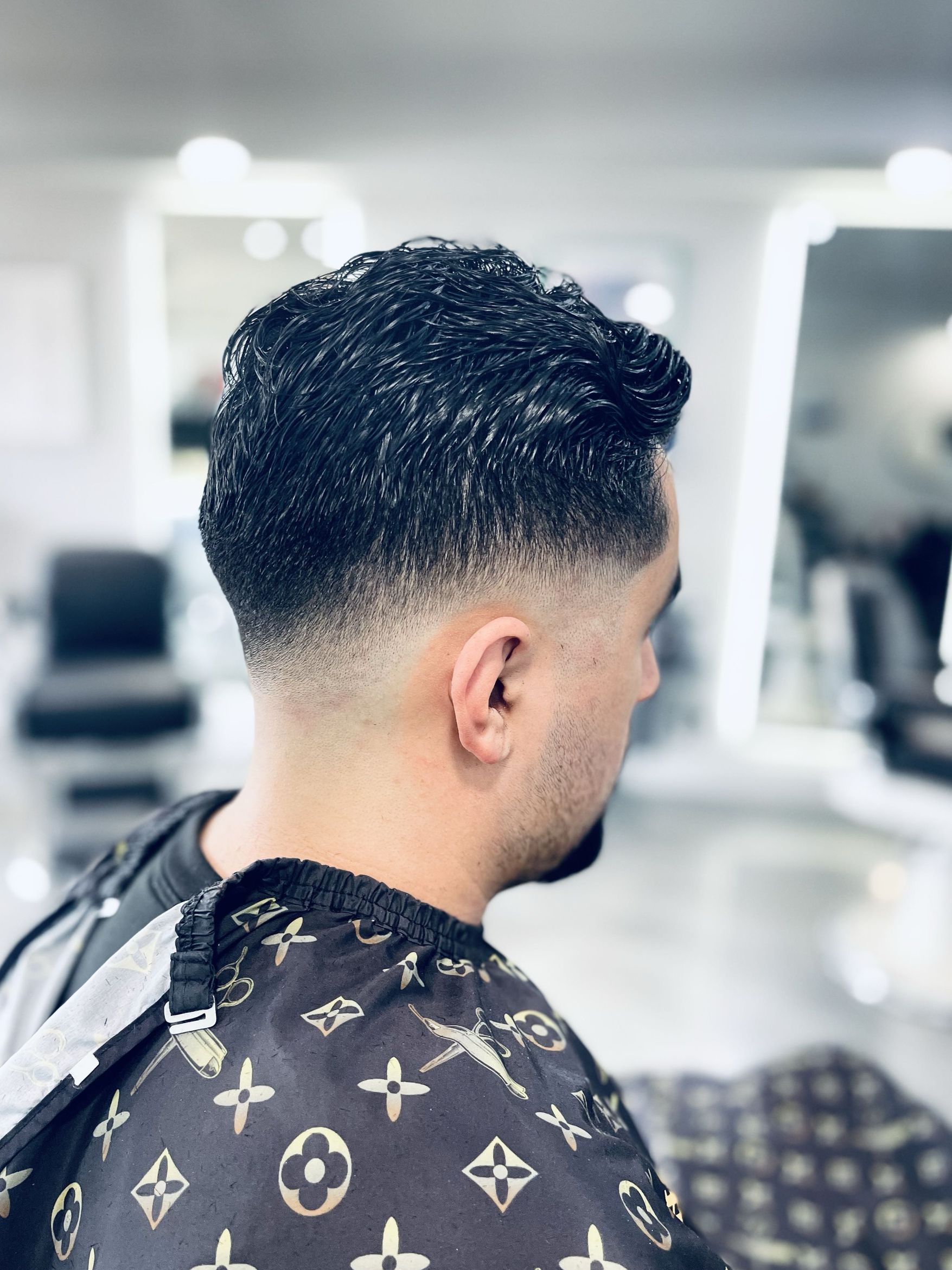 Side profile of a tapered fade cut with textured hair styled on top, finished in a private barber suite