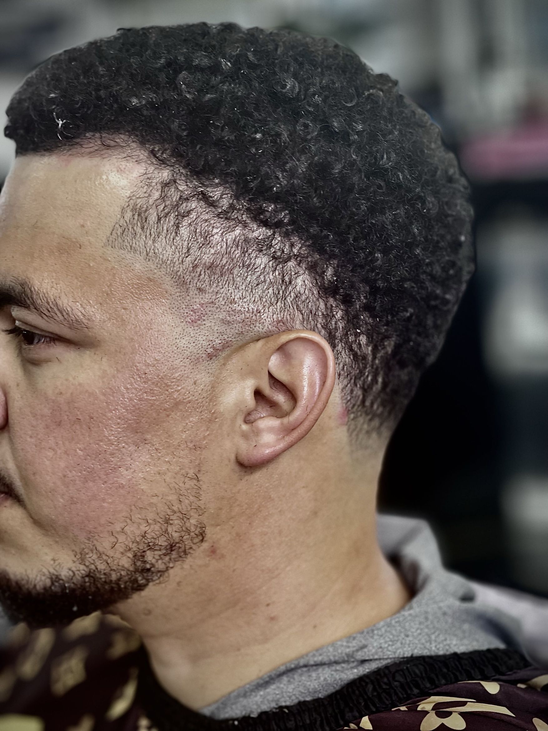 Tight fade on the sides transitioning to natural curly texture on the upper portion of the head