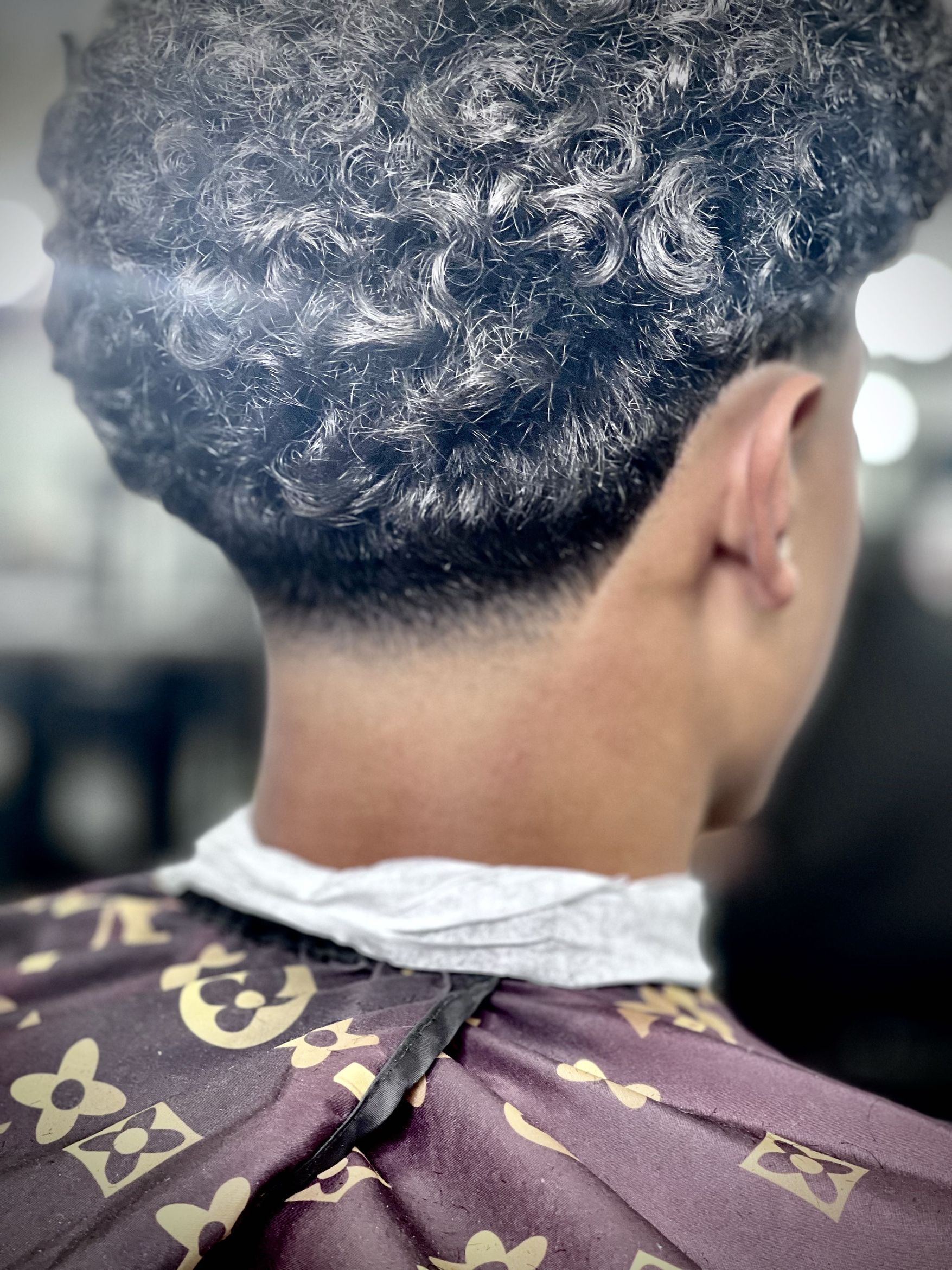 Back-of-head view showing a clean nape taper with curly waves layered on the crown and top