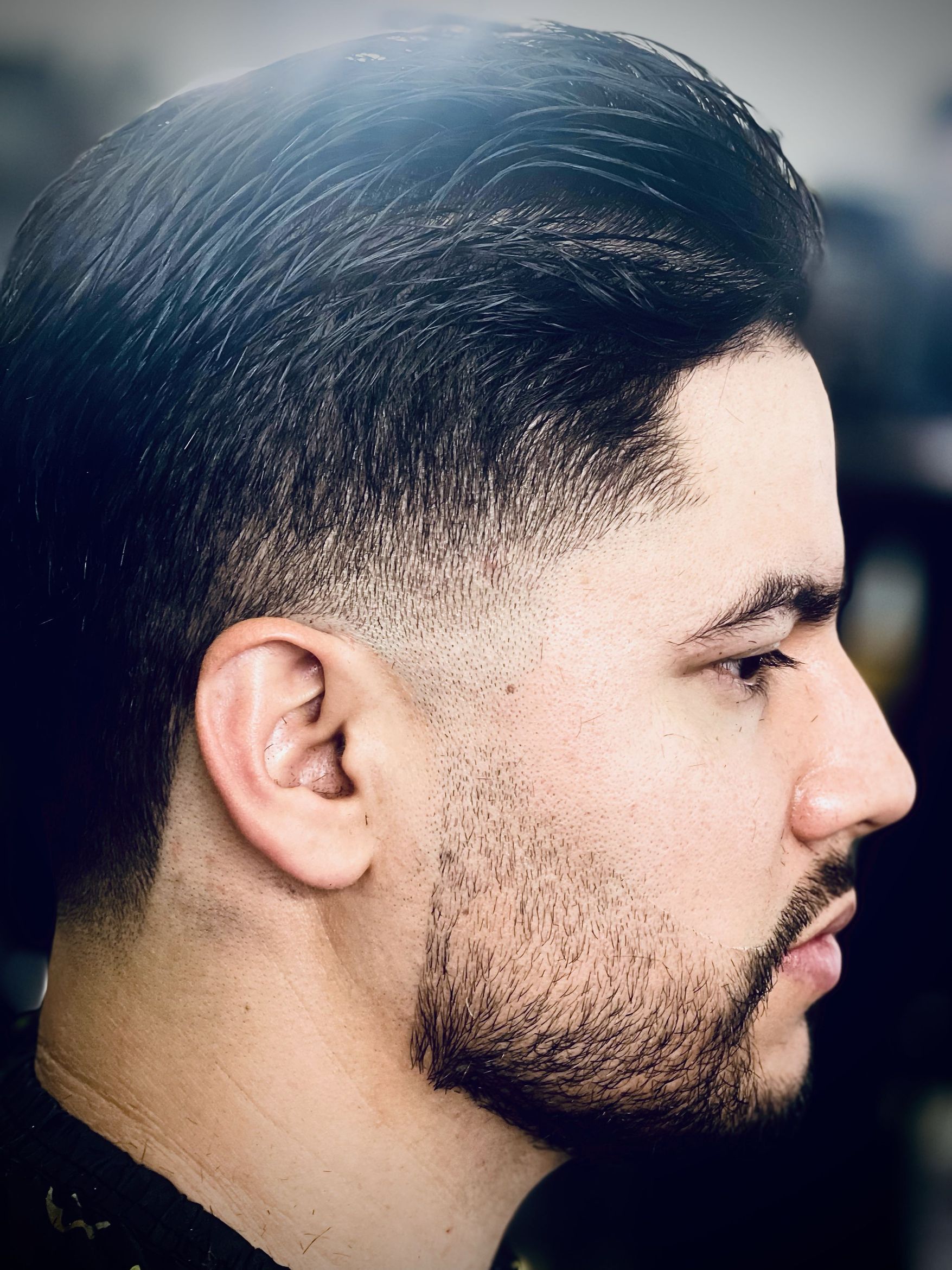Close side profile of a crisp skin fade with short textured crop on top and defined hairline