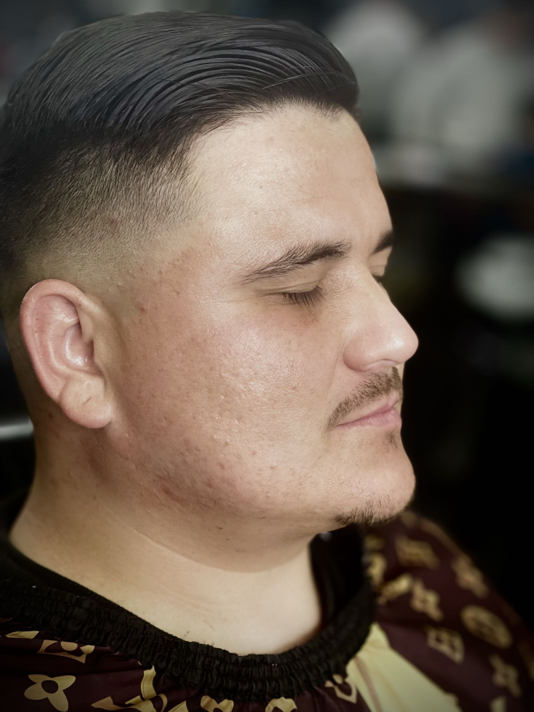 Side profile of a clean mid fade with neatly combed hair on top and a crisp hairline