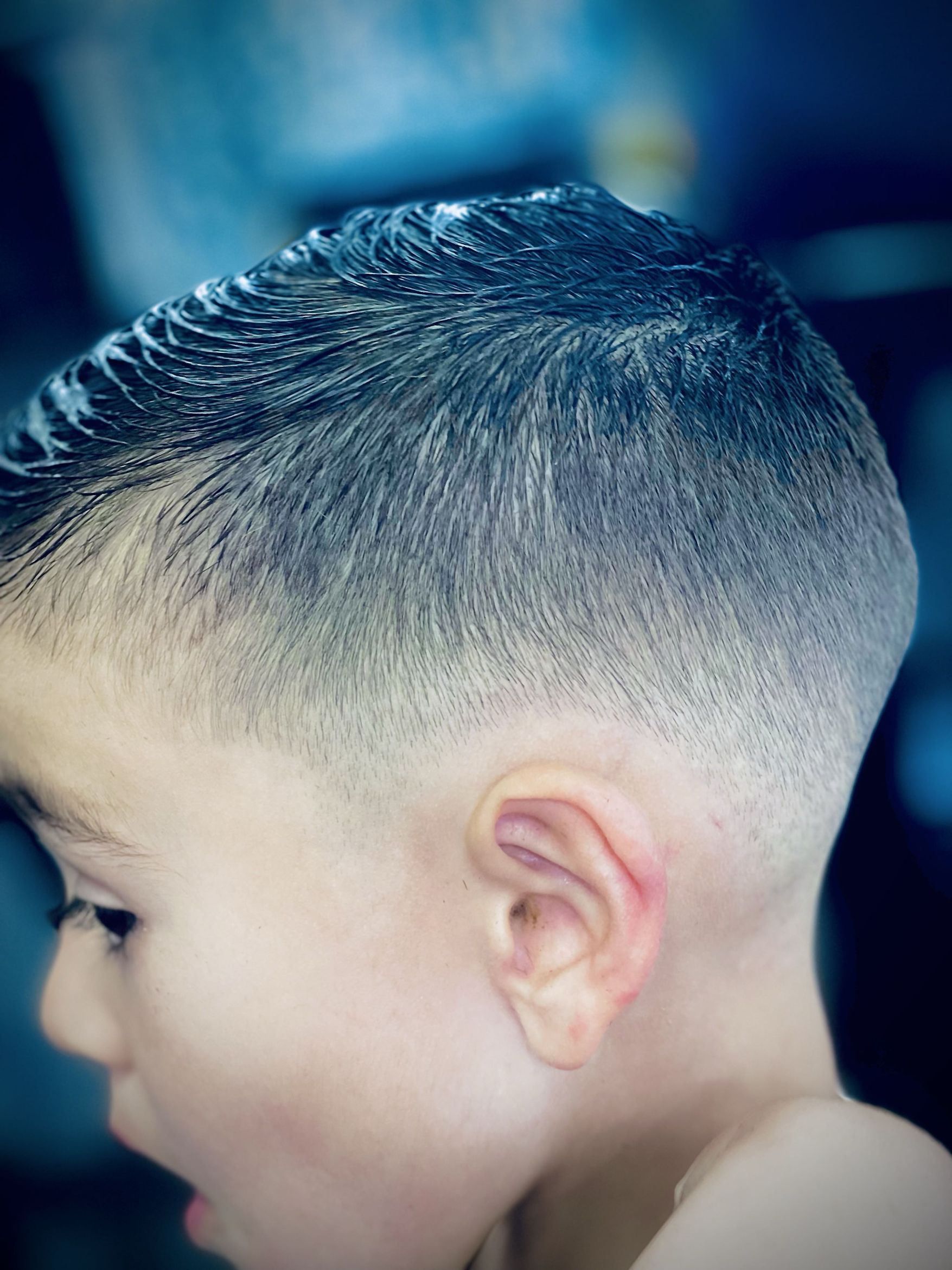 Close-up of a child's fade haircut with clean lines around the ear and tapered sides