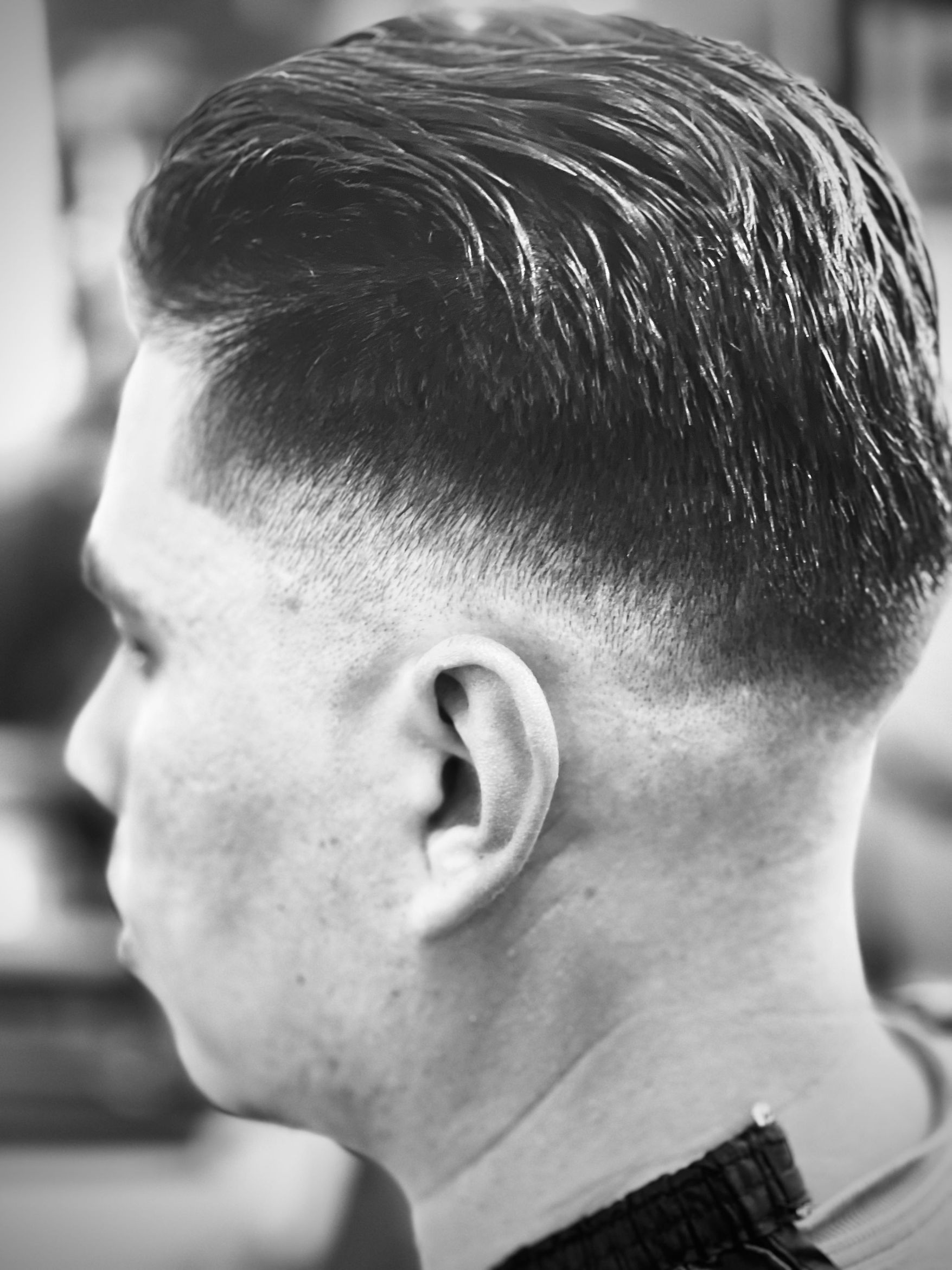 Black and white detail of a tight skin fade with slicked-back textured styling