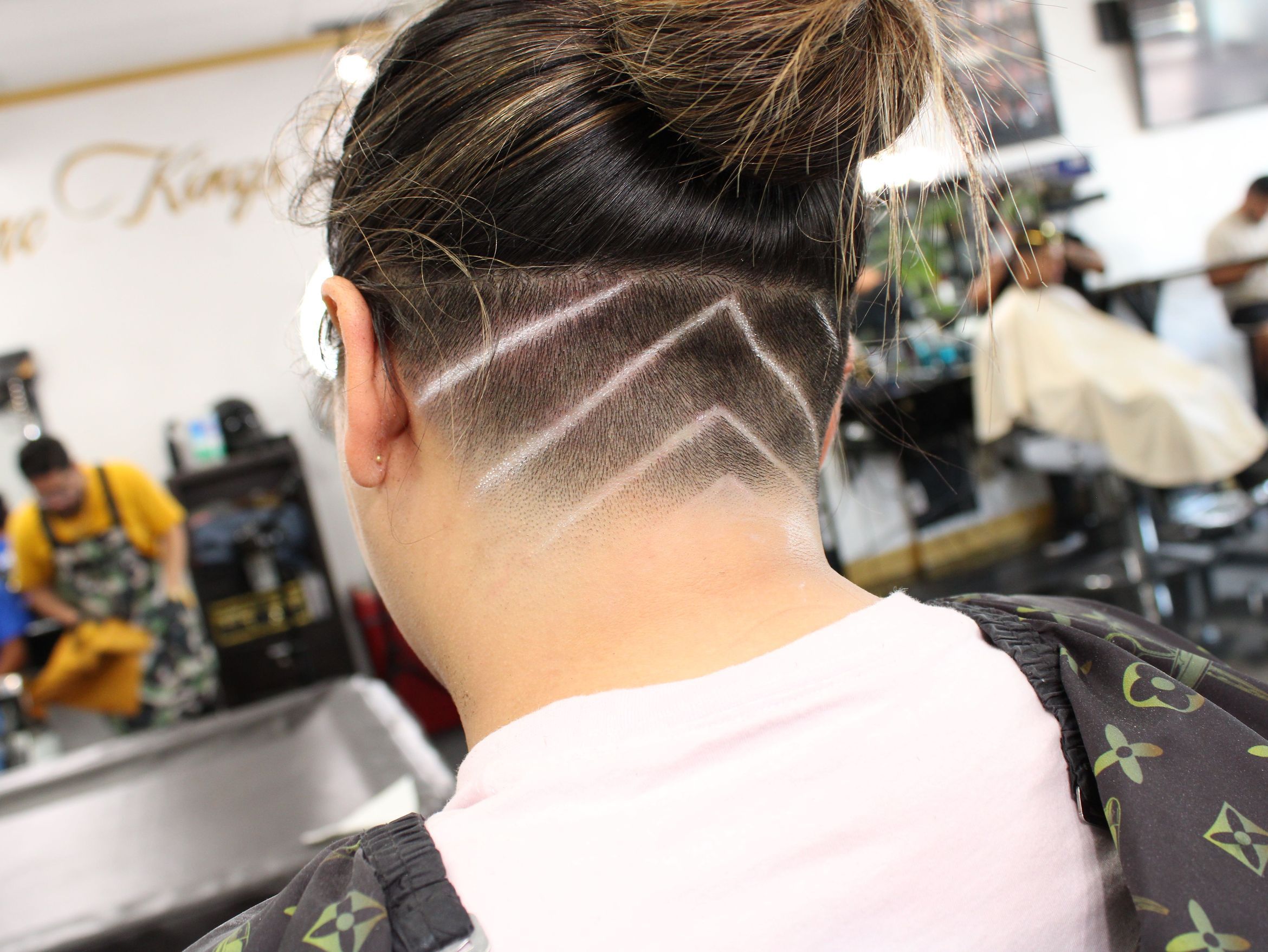 Rear view of an intricate geometric design pattern carved into faded hair with long hair tied up above