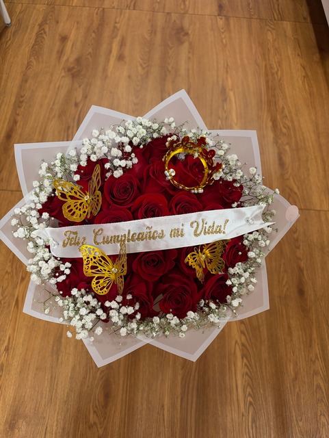 Romantic 25-rose deep red Ecuadorian rose bouquet with sparkling jeweled crown tiara, three golden laser-cut butterfly decorations, white baby's breath border, 'Feliz Cumpleaños mi Vida!' white satin ribbon, and translucent star-point wrap by FridAndre Florals