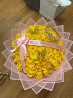 Stunning yellow Ecuadorian rose bouquet with bright sunflowers, sparkling crystal crown tiara, golden laser-cut butterfly decorations, yellow satin ribbon with pearl brooch accent, and white geometric wrap by FridAndre Florals