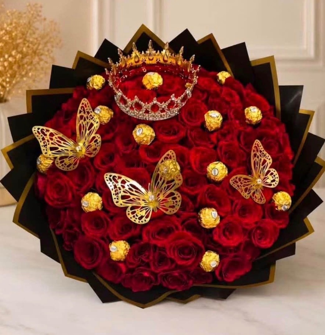 Magnificent 100-rose deep red Ecuadorian rose bouquet with sparkling crystal crown tiara, golden laser-cut butterfly decorations, Ferrero Rocher chocolates nestled among blooms, sleek black geometric paper wrap with gold trim edges - luxury premium chocolate rose gift arrangement by FridAndre Florals