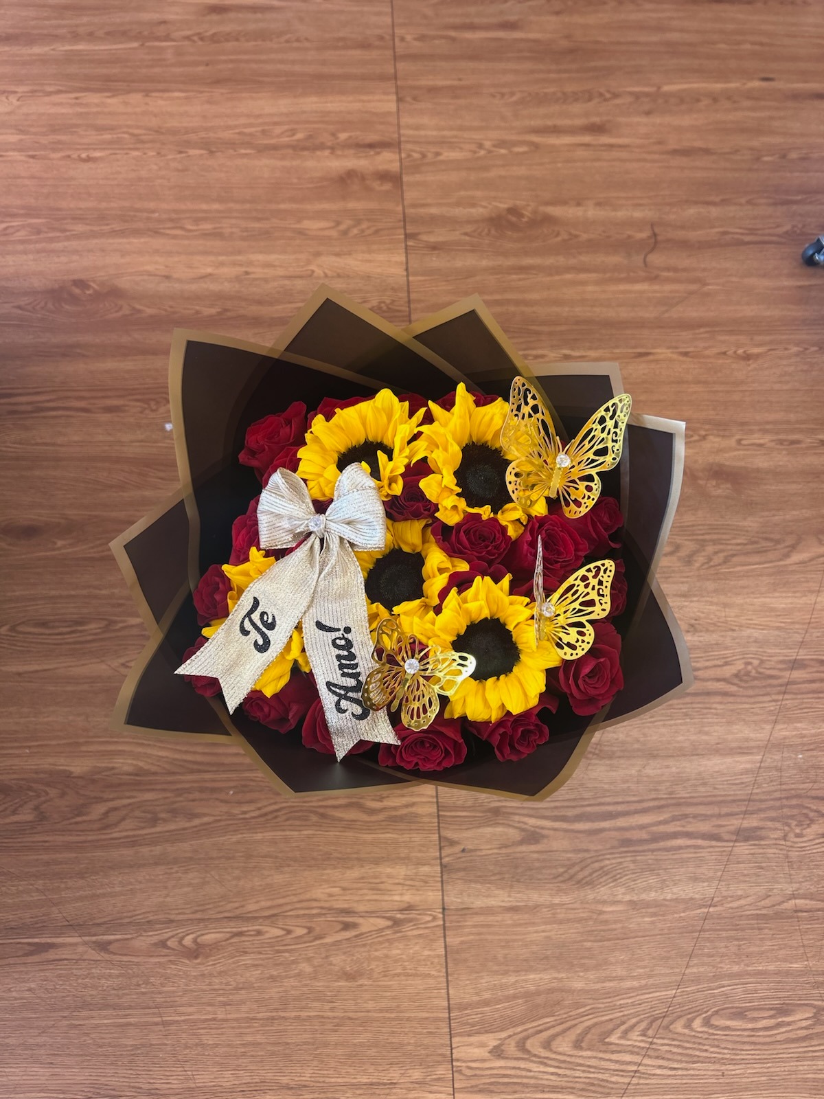 Beautiful 'Te Amo!' red Ecuadorian rose and bright yellow sunflower bouquet with golden laser-cut butterfly decorations, 'Te Amo!' silver sparkle ribbon bow, and dark brown geometric paper wrap - luxury love declaration arrangement by FridAndre Florals