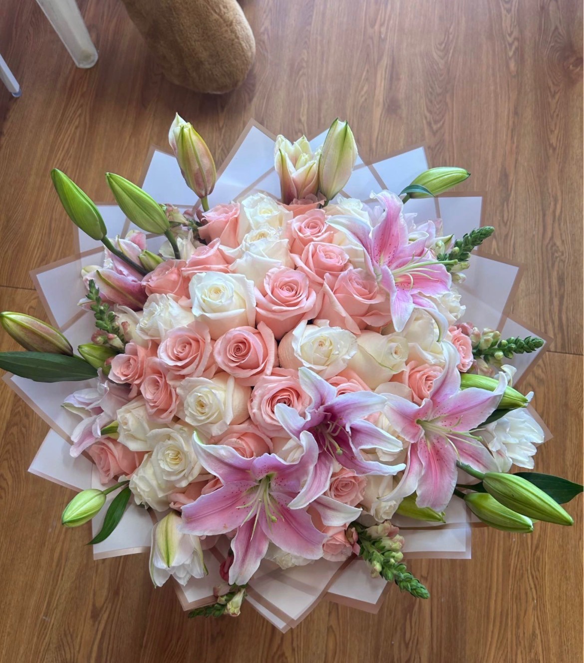 Stunning 50-rose soft pink and cream white Ecuadorian rose bouquet with pink stargazer lily accents, fresh green foliage, delicate snapdragon filler, and elegant white geometric paper wrap - luxury romantic arrangement by FridAndre Florals