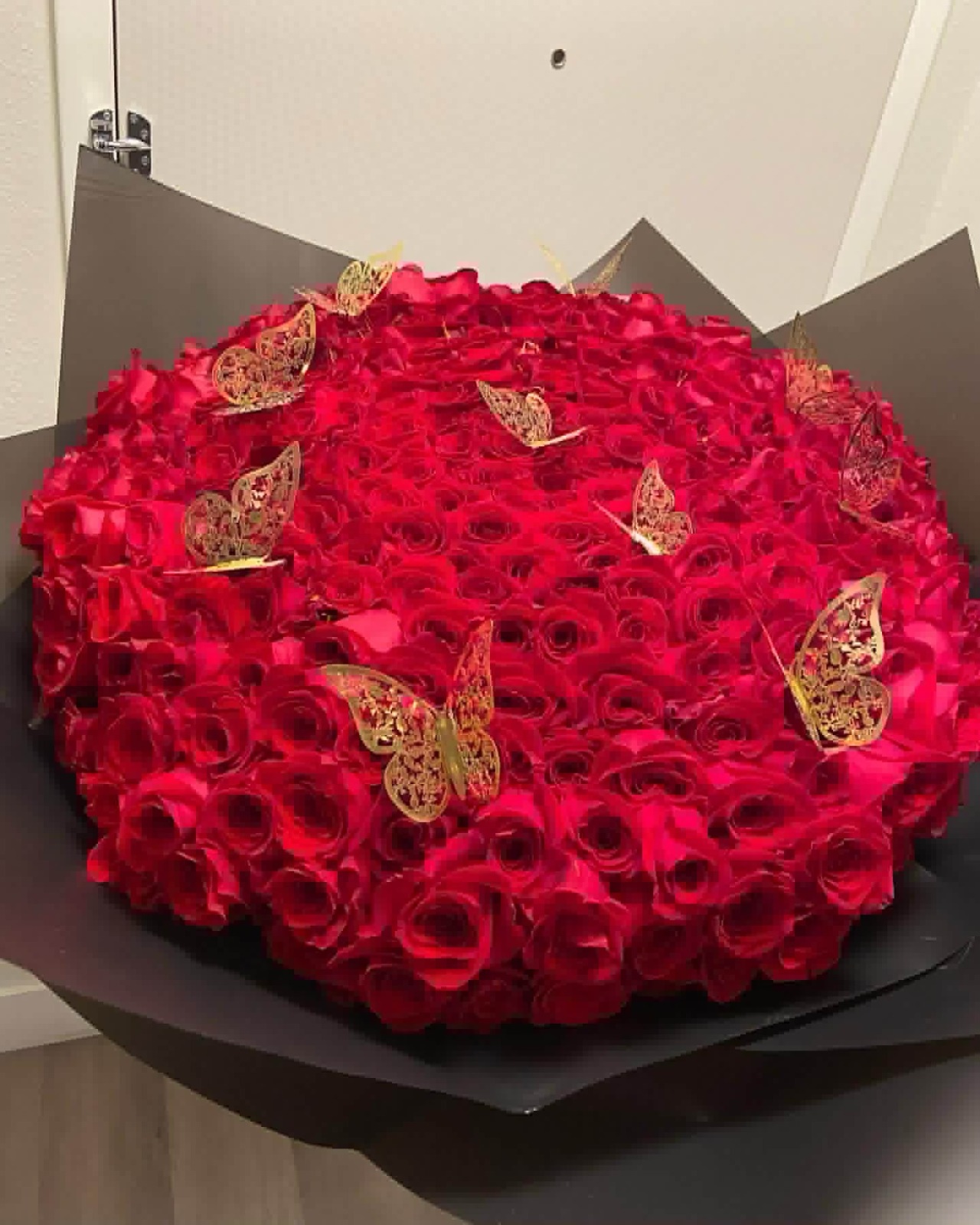 Massive 200-rose deep red Ecuadorian round bouquet with golden laser-cut butterfly decorations, sleek black geometric paper wrap - ultra premium luxury arrangement for grand romantic gestures