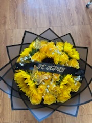 Vibrant yellow rose and sunflower bouquet with golden laser-cut butterflies and '¡TE AMO!' silver sparkle black ribbon in black star-point wrap by FridAndre Florals