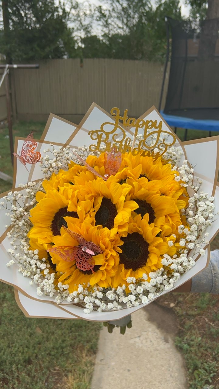 Cheerful sunflower bouquet framed with baby's breath, 'Happy Birthday' golden topper, and pink butterfly accents in white and gold star-point wrap by FridAndre Florals