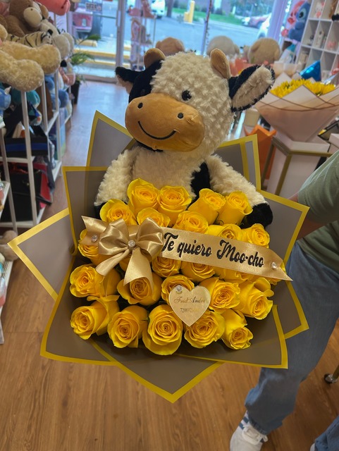 Plush cow bouquet with 25 yellow Ecuadorian roses, gold ribbon with 'Te quiero Moo-cho' script, gold bow, and FridAndre gold heart accent