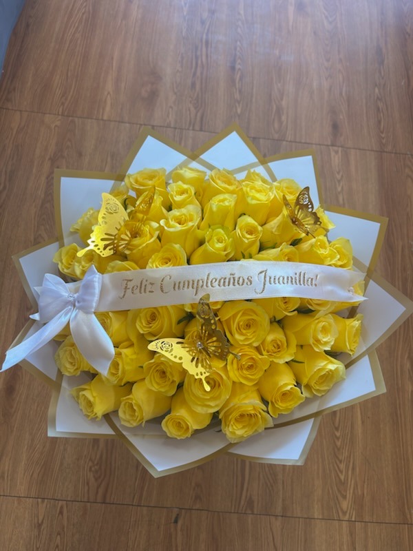 Stunning yellow Ecuadorian rose bouquet adorned with golden laser-cut butterflies, white satin bow, and custom 'Feliz Cumpleaños Juanilla!' ribbon in white and gold star-point wrap by FridAndre Florals