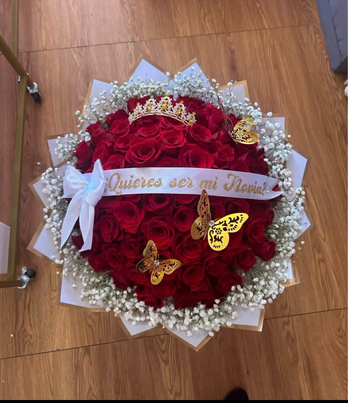Romantic '¿Quieres ser mi Novia?' 50-rose deep red Ecuadorian rose bouquet with sparkling crystal crown tiara, golden laser-cut butterfly decorations, white baby's breath border, '¿Quieres ser mi Novia?' gold-glitter lettered satin ribbon bow, and elegant white geometric paper wrap - luxury proposal arrangement