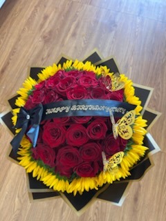 Stunning bouquet of deep red roses framed by bright golden sunflowers, golden laser-cut butterflies, and 'HAPPY BIRTHDAY LUCY' ribbon in black star-point wrap by FridAndre Florals