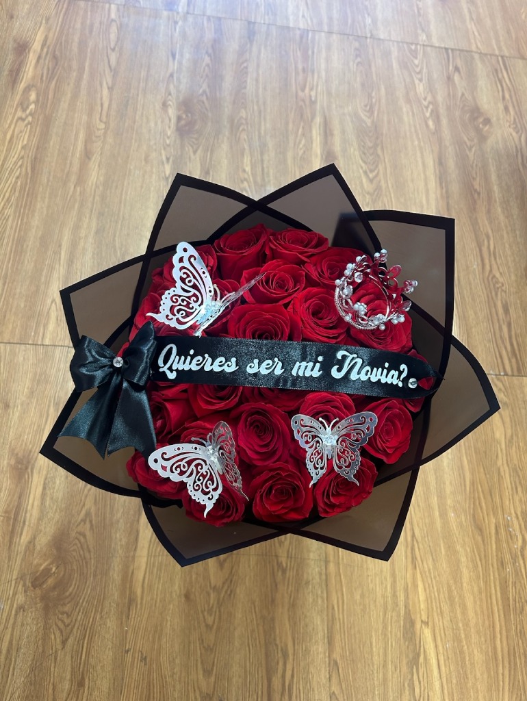 Romantic '¿Quieres ser mi Novia?' 25-rose deep red Ecuadorian round rose bouquet with sparkling crystal crown tiara, two silver laser-cut butterfly decorations, '¿Quieres ser mi Novia?' silver script black satin ribbon bow, and sleek black geometric paper wrap - luxury proposal arrangement by FridAndre Florals