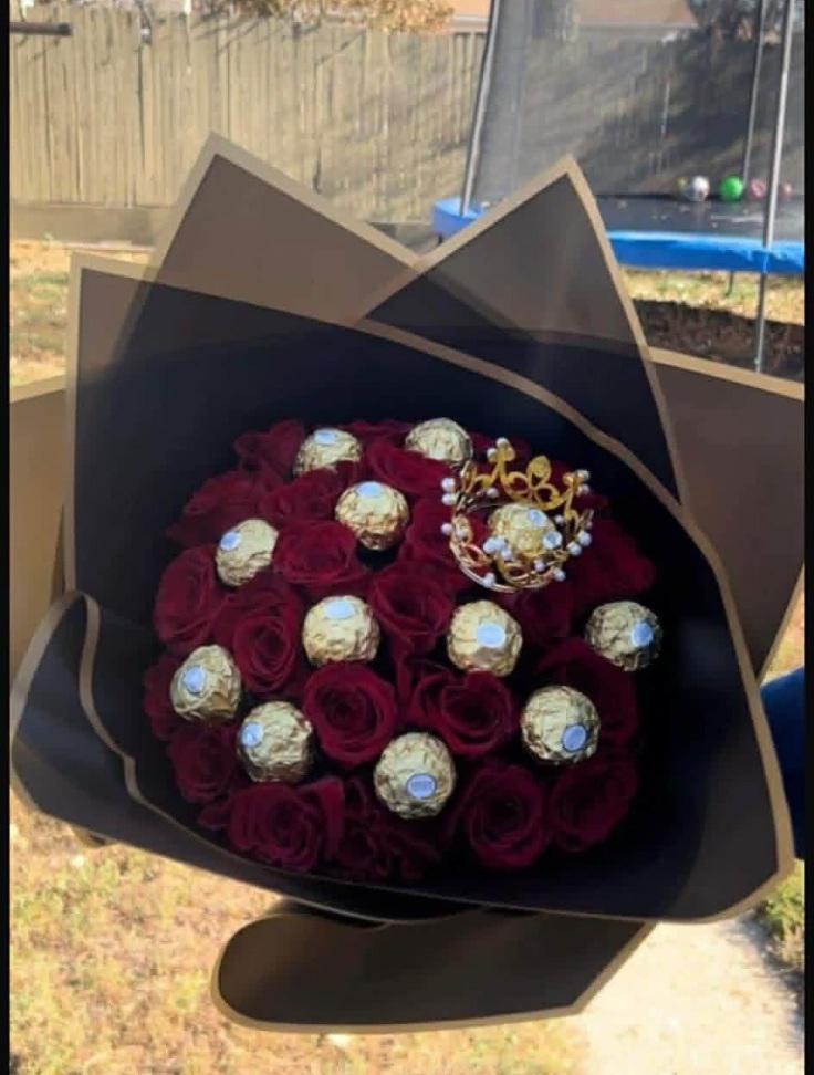 Elegant 25-rose deep red Ecuadorian rose bouquet with 12 Ferrero Rocher chocolates arranged in crown pattern among blooms, sparkling crystal crown tiara with pearl accents, sleek black geometric paper wrap - luxury chocolate rose gift arrangement by FridAndre Florals