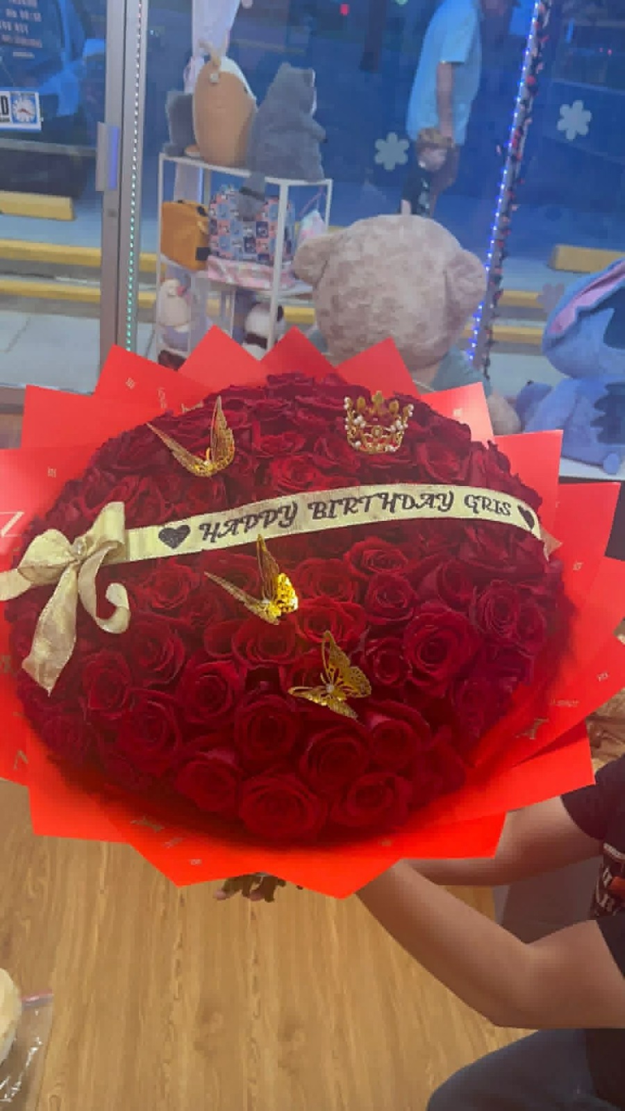 Stunning 'Happy Birthday Cris!' 100-rose deep red Ecuadorian round rose bouquet with sparkling crystal crown tiara, four golden laser-cut butterfly decorations, 'Happy Birthday Cris' gold-lettered cream satin ribbon bow, and vibrant red geometric paper wrap - luxury birthday celebration arrangement by FridAndre Florals