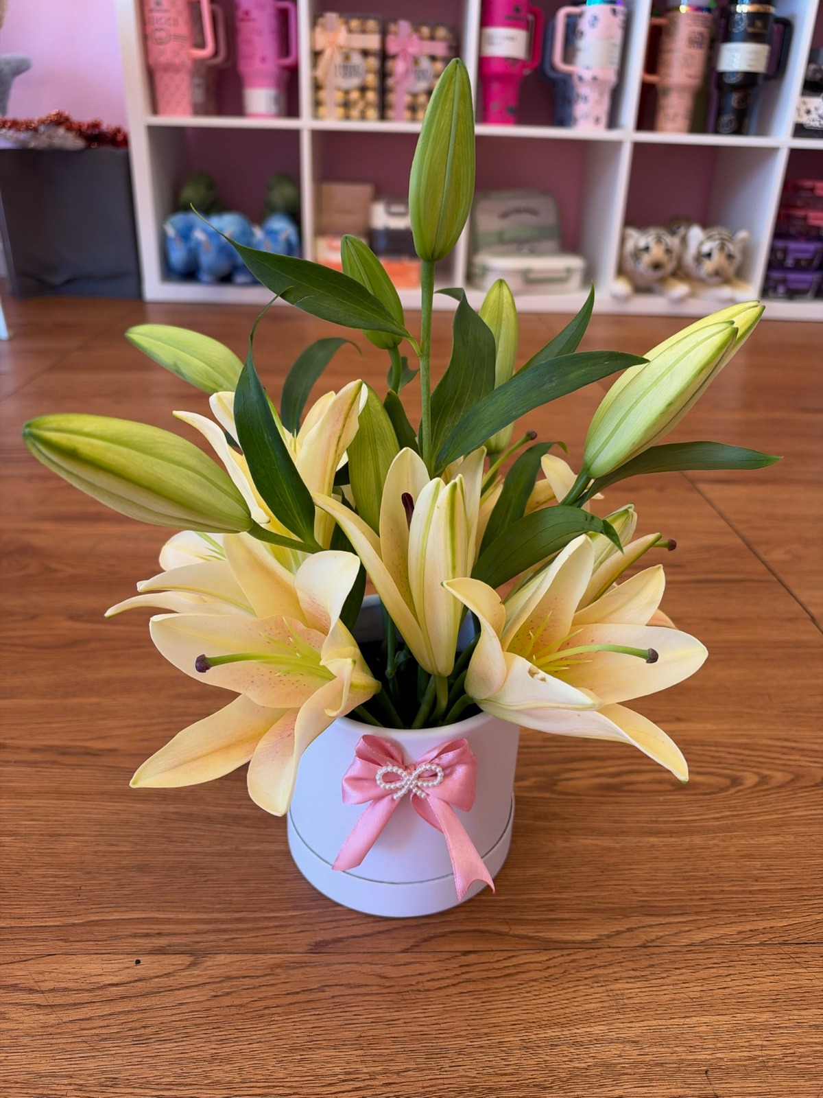 Fresh yellow Asiatic lilies in a white cylinder hat box with pink satin ribbon and pearl accent by FridAndre Florals