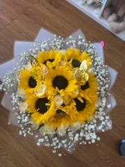 Beautiful bouquet of bright sunflowers and vibrant yellow Ecuadorian roses with golden butterflies and white geometric paper wrap by FridAndre Florals