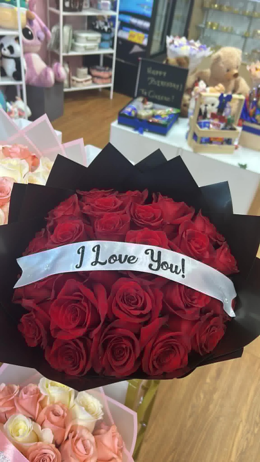 Romantic 'I Love You!' 25-rose deep red Ecuadorian round rose bouquet with 'I Love You!' silver script satin ribbon bow, sleek black geometric paper wrap, and fresh green foliage base - love declaration arrangement by FridAndre Florals