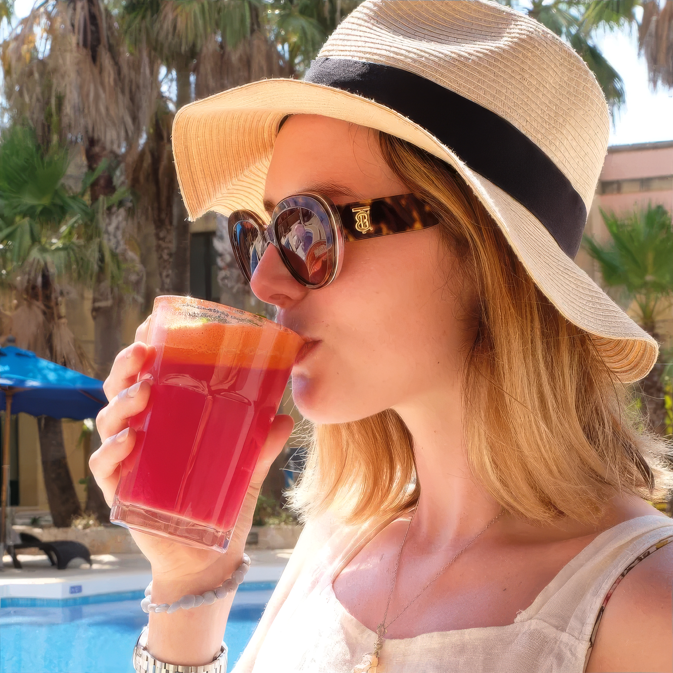 Guest in a sunhat enjoying a fresh healthy juice by the pool