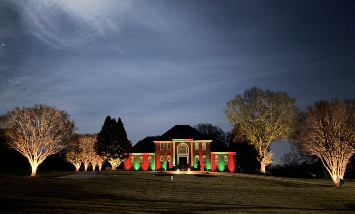Professionally installed landscape uplighting illuminating a home at dusk in Greenville SC
