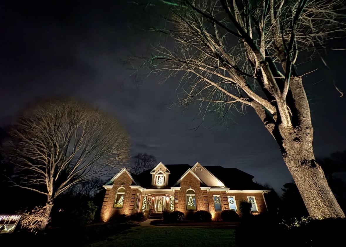 Luxury two-story brick estate with custom architectural uplighting and tree illumination in Greenville SC