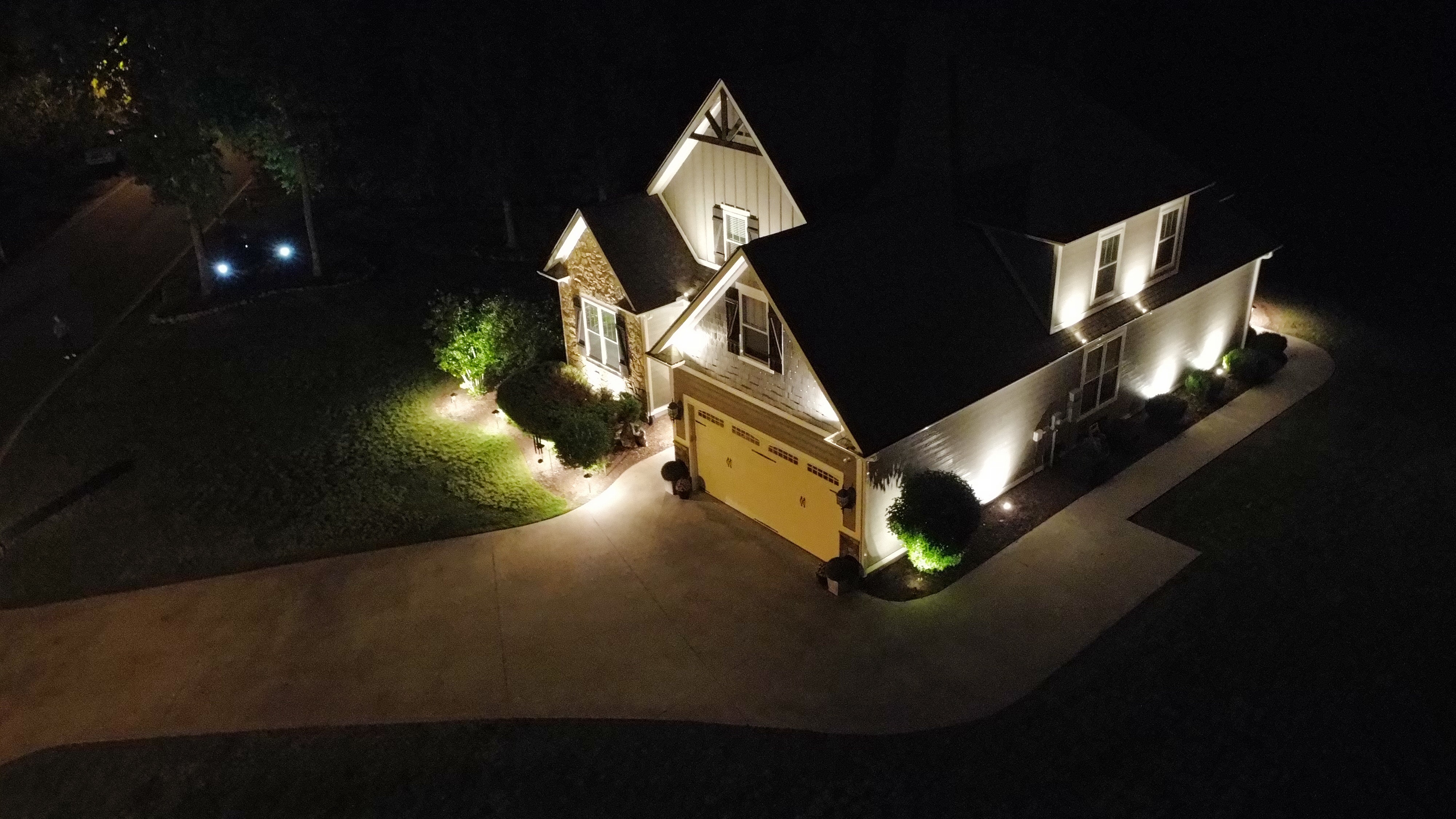 Angled aerial view showing driveway, facade, and garden bed landscape uplighting in Simpsonville SC