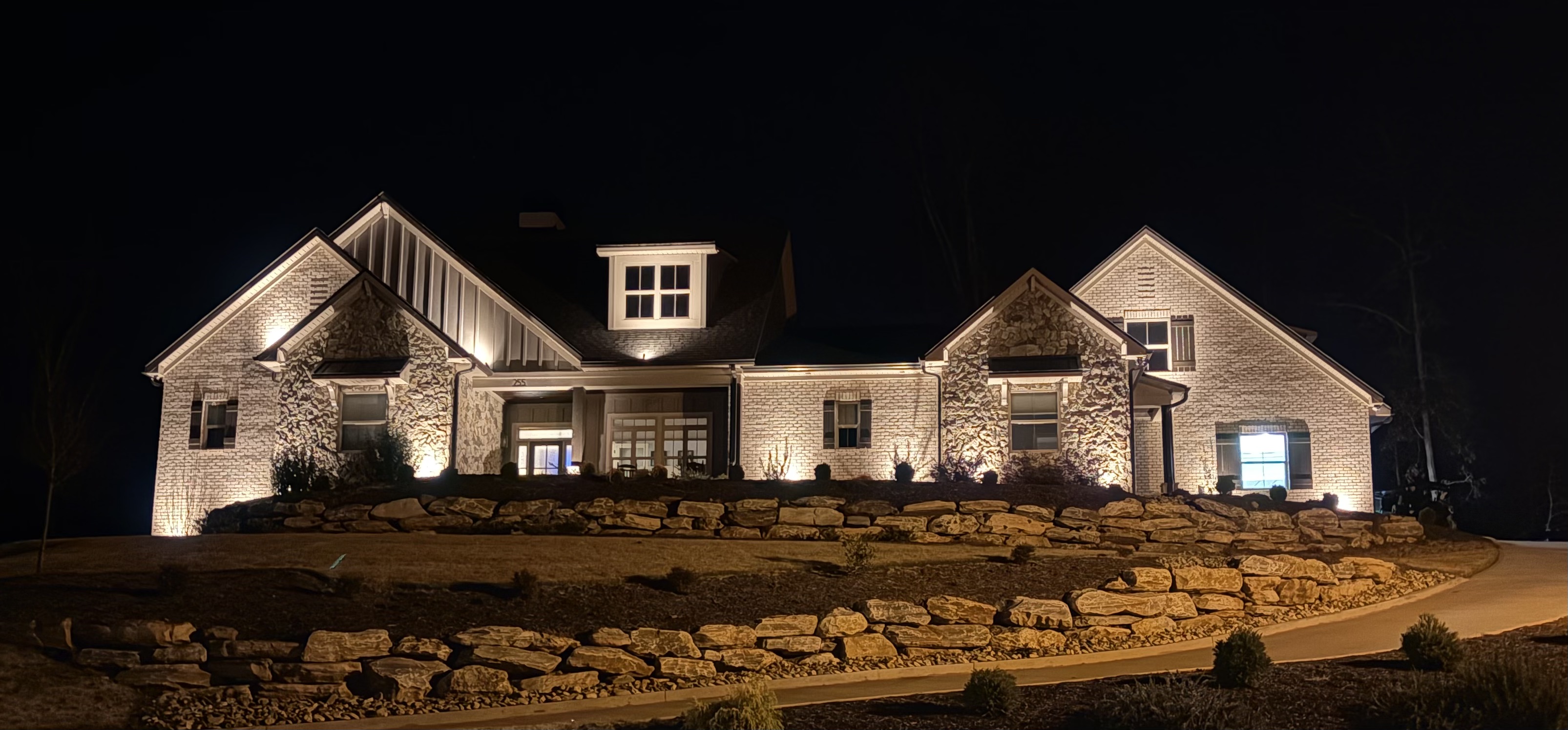 Grand hillside luxury residence with illuminated natural stone retaining walls and full facade uplighting in Greenville SC