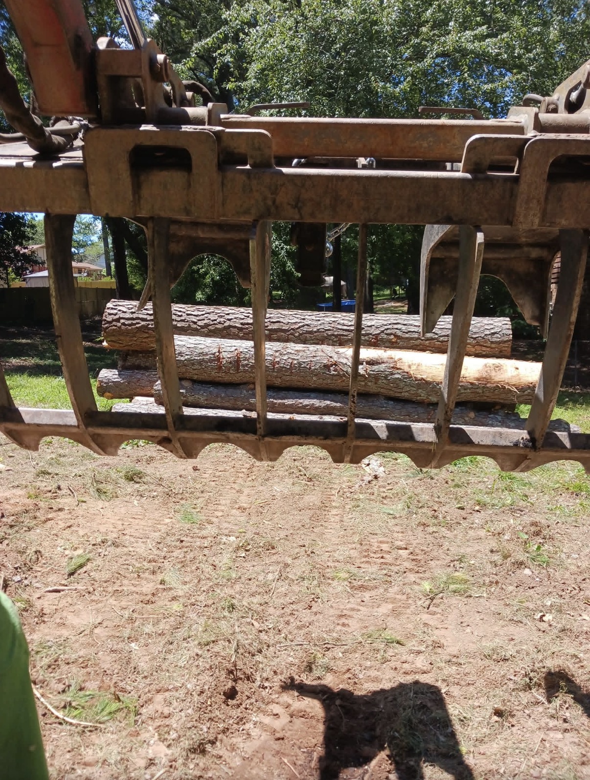 Close-up of a grapple loader attachment loaded with cut tree logs for hauling
