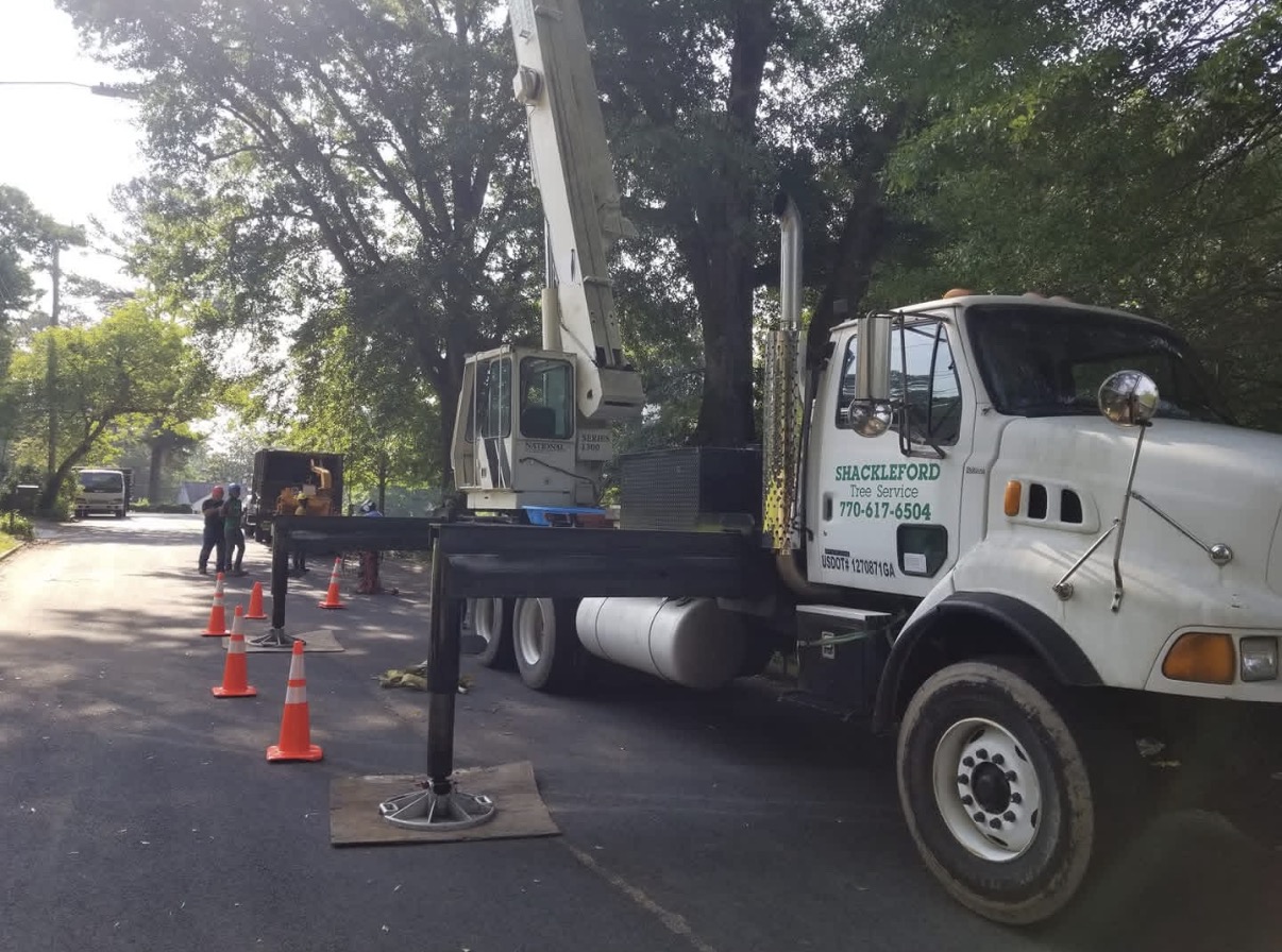 Shackleford Tree Service crane truck with outriggers set up on a residential street for a tree job