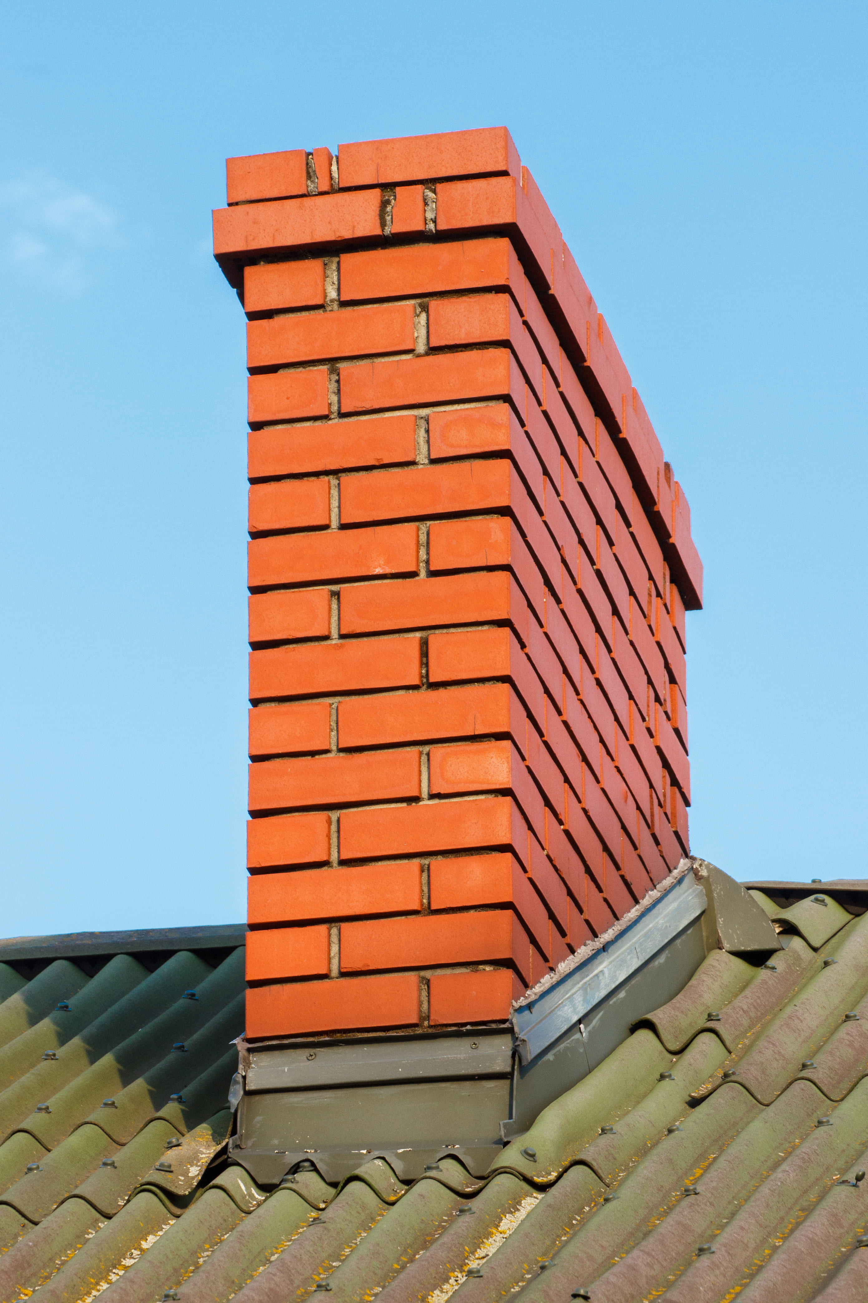 Brick chimney against blue sky with cowl visible