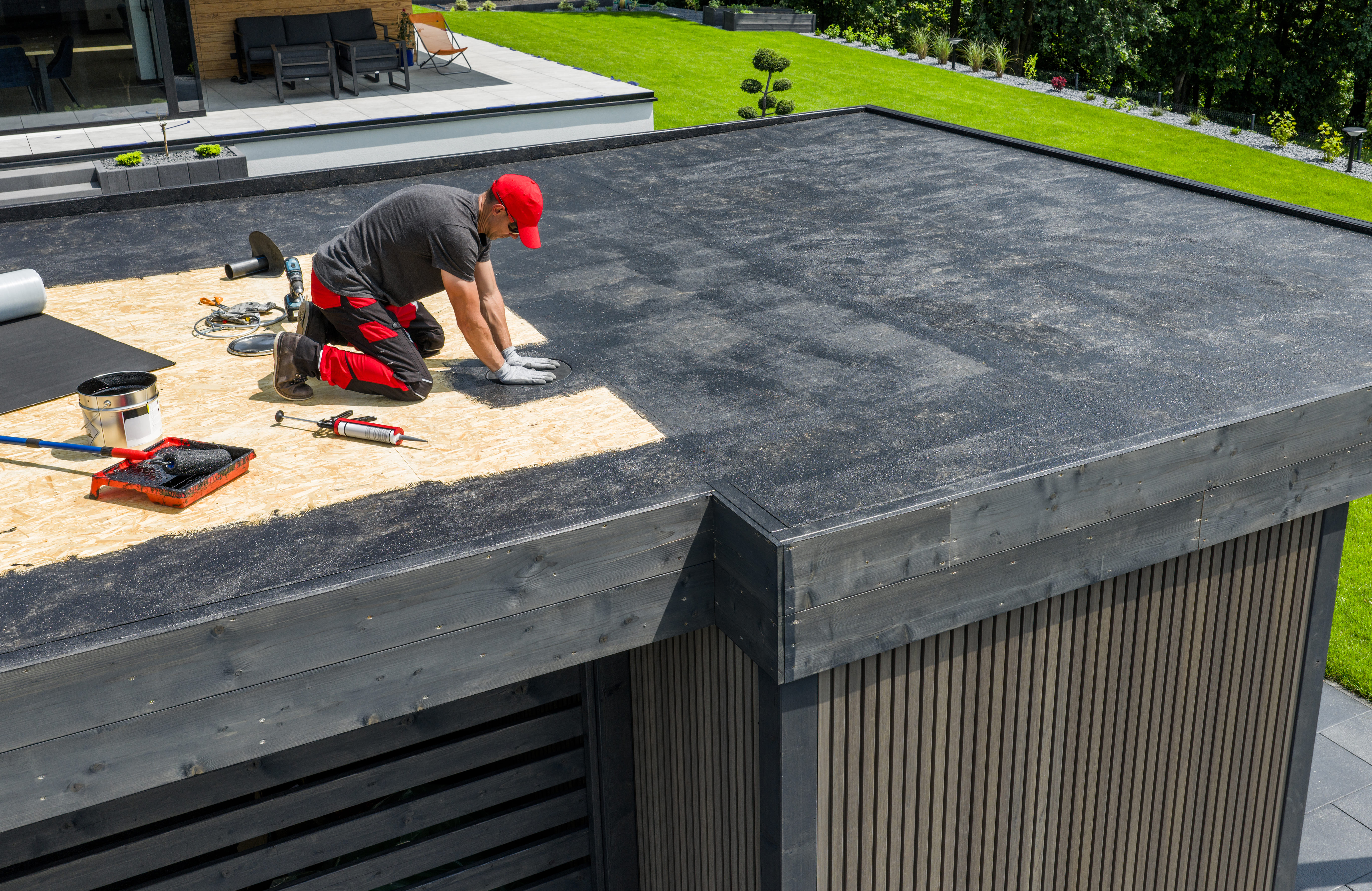 Installer fitting flat roof membrane on garden building