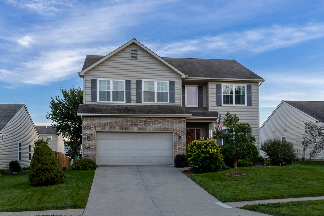 HDR front exterior photograph of two-story home with attached garage and lush green lawn in Fort Wayne, IN